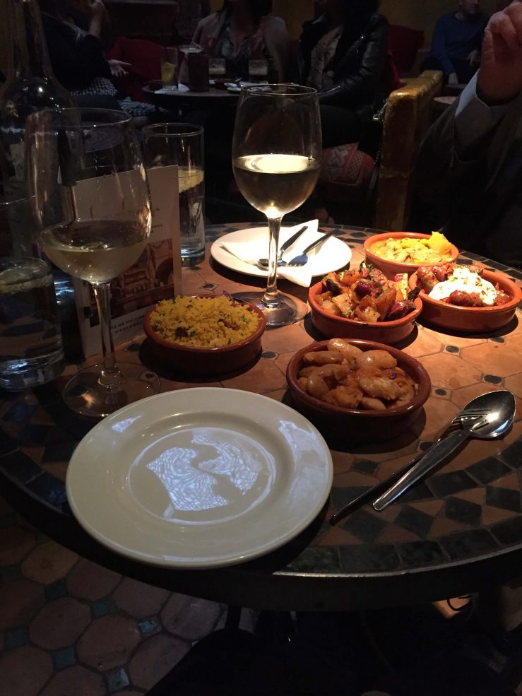 A tapas meal laid out on a round table. With white wine. 